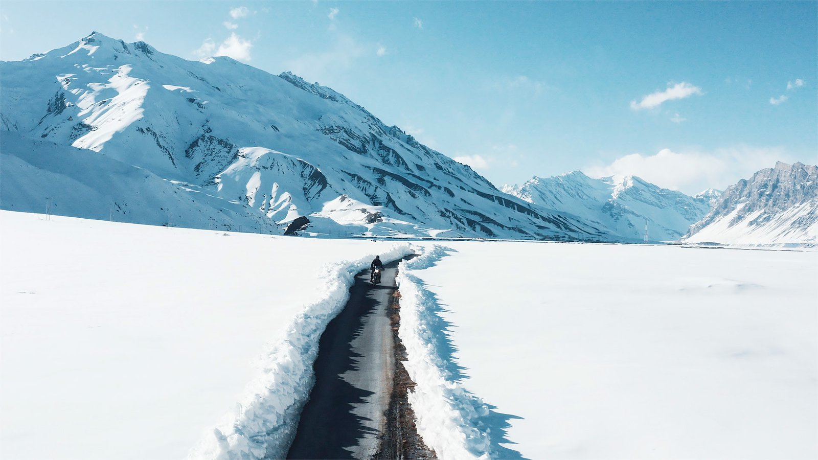 A lone rider on a narrow road through the snow-covered Himalayas, from QUROST’s work